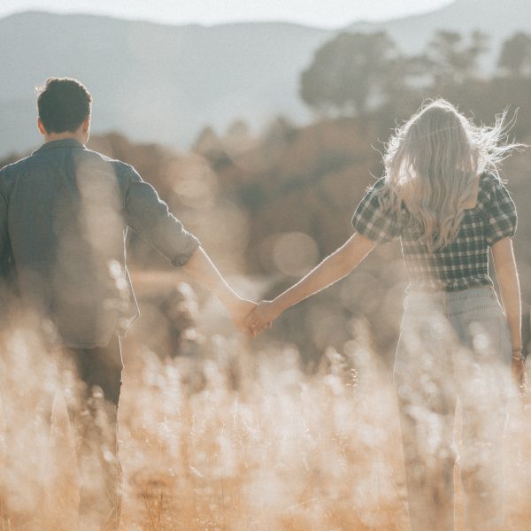 couple walking in field holding hands
