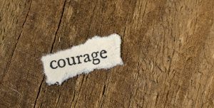 word courage on wooden background